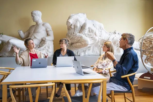 Fyra personer sitter vid ett bord och pratar engagerat. Foto.
