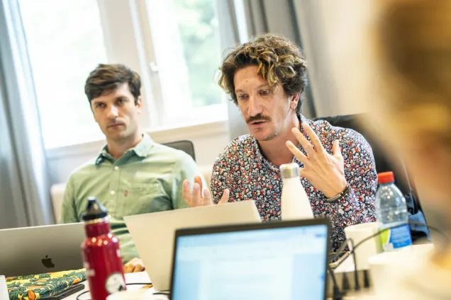 Två unga män sitter vid bord med laptops.