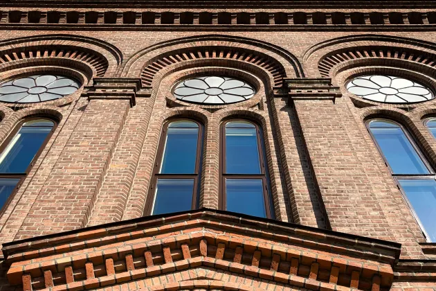 Photo taken upwards on a red brick facade with large beautiful windows.