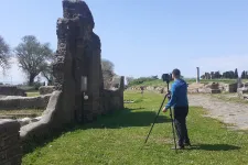 A person takes a photo of the ruins of the ancient synagogue at Ostia, Italy. Daytime. Photo.  
