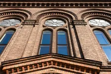 Photo taken upwards on a red brick facade with large beautiful windows.