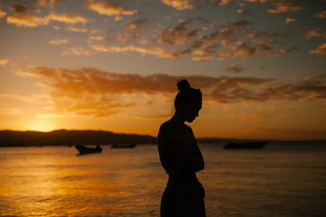 kvinna vid havet vid solnedgång. Foto.